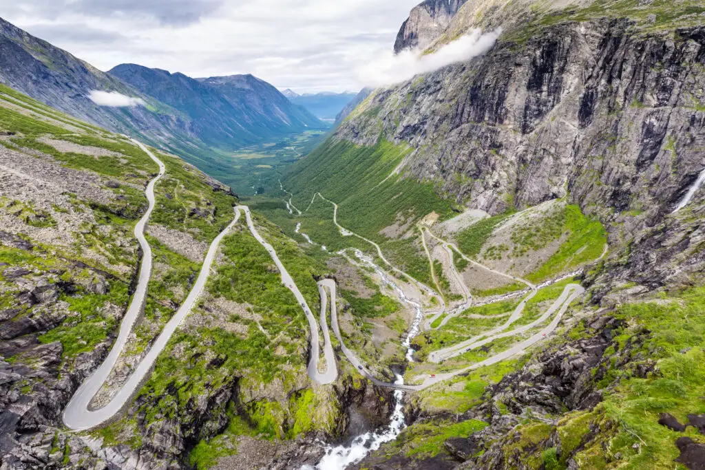 Aerial view of Trollstigen, the serpentine mountain road and popular tourist attraction in Norway, showcasing lush landscapes and dramatic waterfalls.