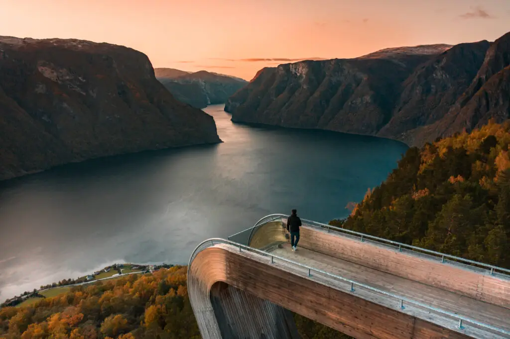 Tourist experiencing the breathtaking sunset view over Aurlandsfjord from Stegastein Lookout in Norway