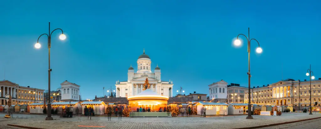 Winter night view of a holiday market with carousel on Senate Square in Helsinki, Finland, featuring the illuminated Lutheran Cathedral