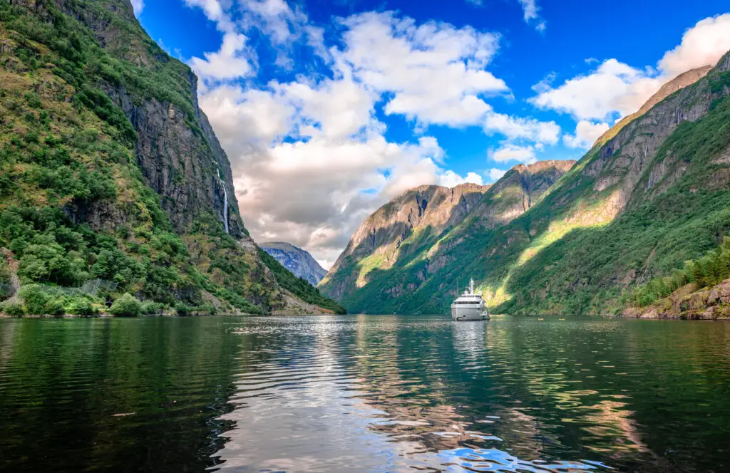 Tourboat sailing in Aurlandsfjord, a picturesque branch of Sognefjorden with towering cliffs and cascading waterfalls, showcasing the breathtaking landscapes of Norway.