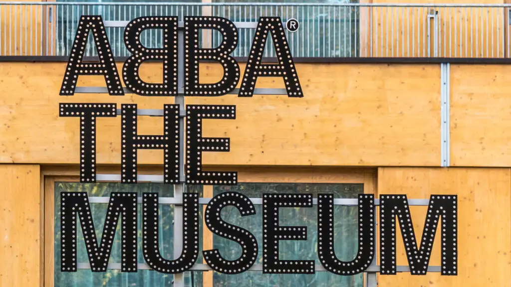 Entrance sign of ABBA The Museum in Stockholm, Sweden, featuring distinctive lit-up letters on a wooden facade.