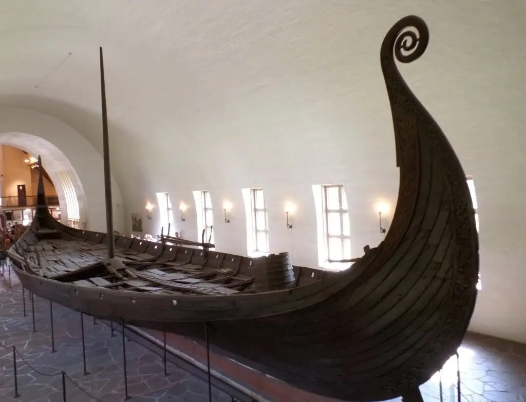 Well-preserved Oseberg Viking ship displayed at the Viking Ship Museum in Oslo, Norway, showcasing intricate wood carvings and historical craftsmanship.