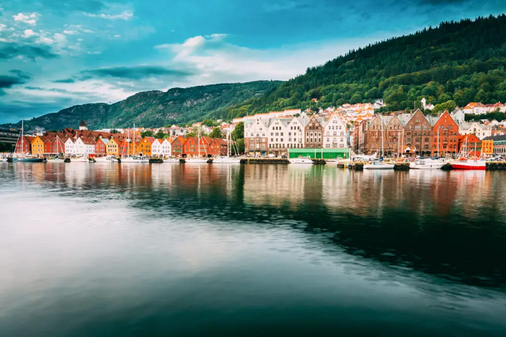 Historical colorful wooden buildings of Bryggen reflecting on the calm waters at the Hanseatic Wharf in Bergen, Norway, a popular Scandinavian tourism destination.