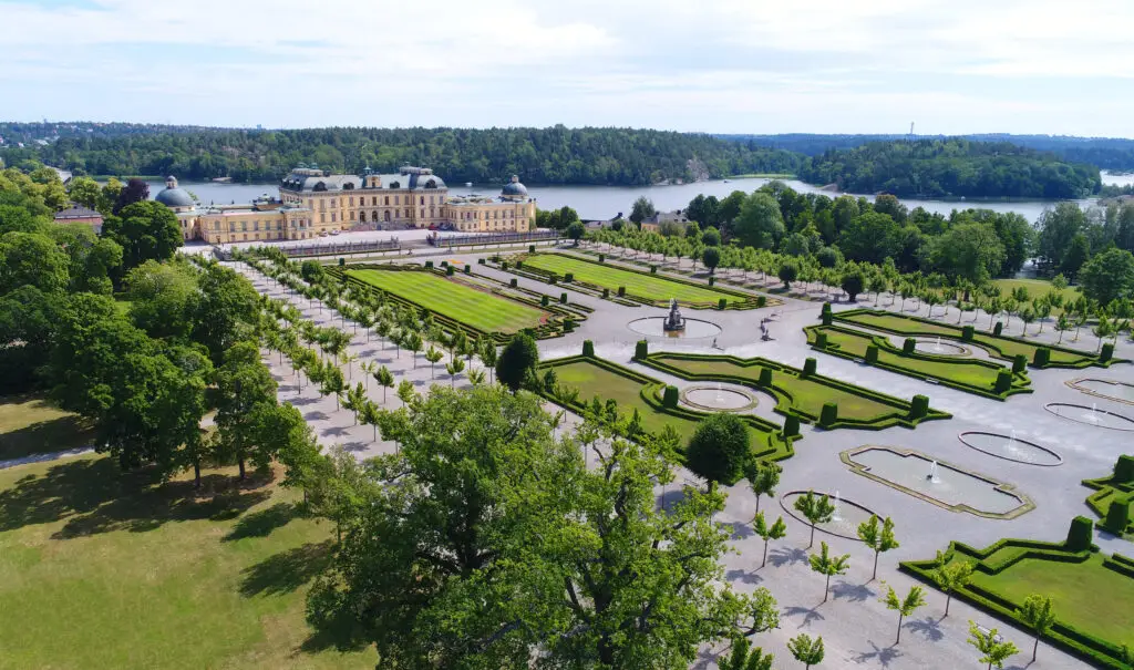 Aerial view of Drottningholm Palace and its intricate gardens in Stockholm, Sweden, showcasing the baroque architectural style and lush greenery perfect for a Scandinavian cultural tour.