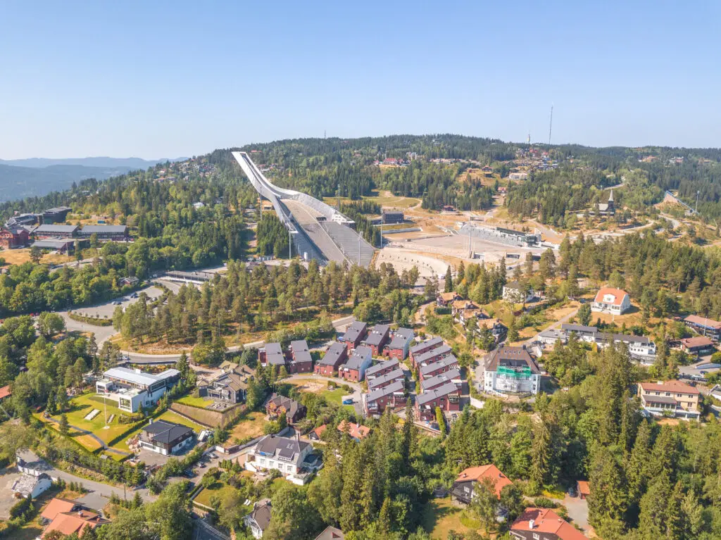 Aerial view of Holmenkollen borough in Oslo featuring the iconic Ski Museum and Ski Jump Tower among lush greenery and residential areas.