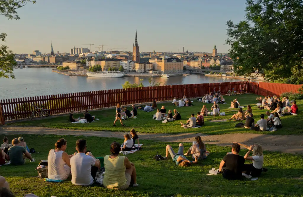 Young people enjoying a sunset picnic in Södermalm, overlooking the scenic skyline of Stockholm, Sweden.