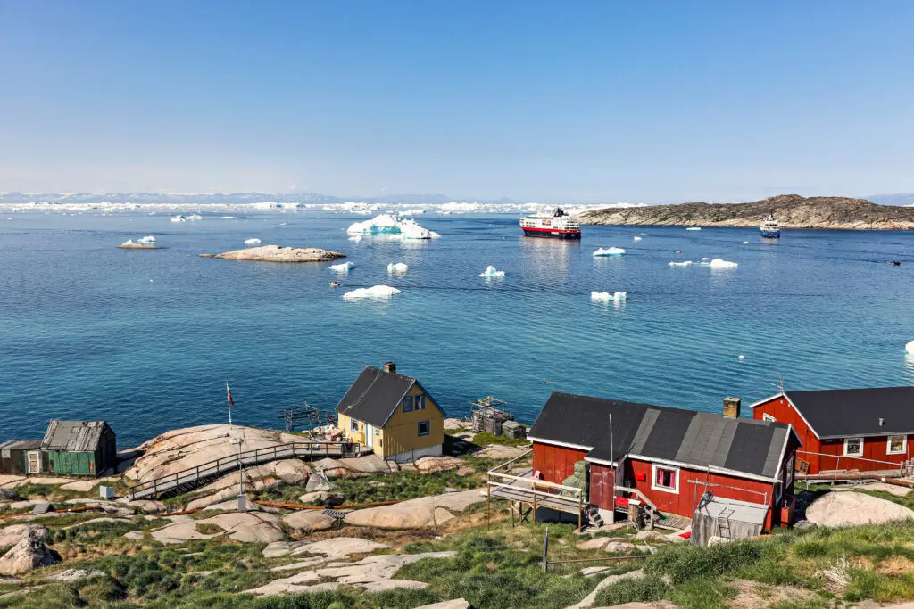 Scenic view of Ilulissat town with colorful houses overlooking icebergs in Disko Bay, West Greenland, a popular tourist destination in Scandinavia.