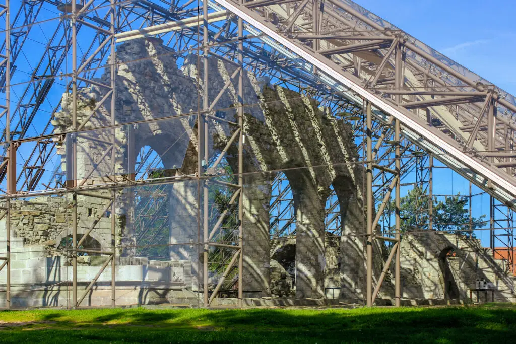 Historic ruins of Hamar Cathedral enclosed in a protective glass and steel structure under a blue sky in Norway, showcasing medieval architecture preservation.