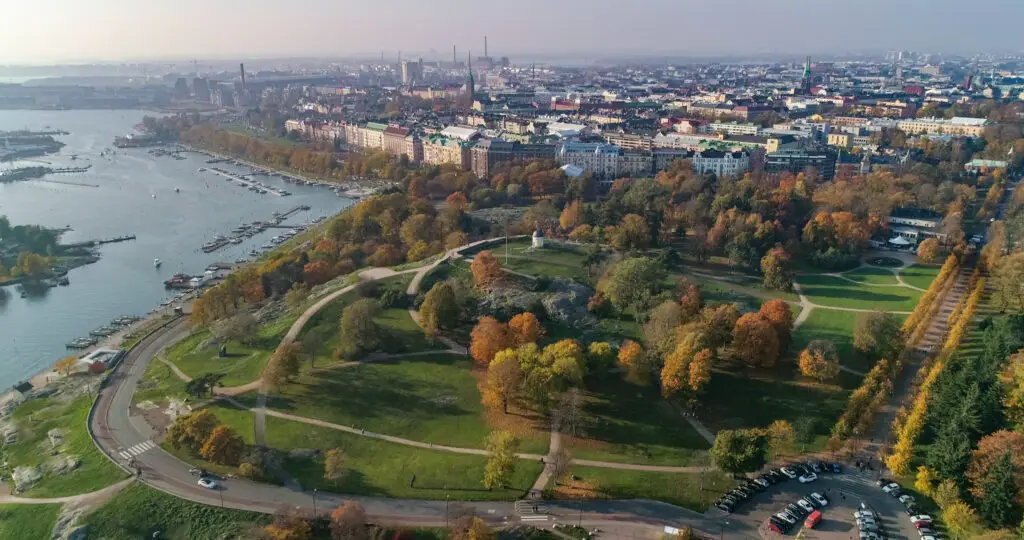 Aerial view of Kaivopuisto Park in Helsinki, Finland on a sunny autumn day, showcasing vibrant fall foliage and cityscape.