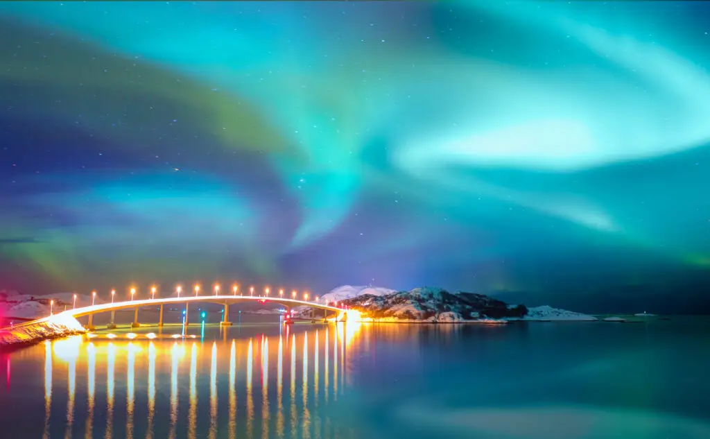 Aurora Borealis over Sommaroy Bridge connecting Kvaloya and Sommaroy islands in Tromso, Norway, showcasing a vibrant night sky and scenic winter landscape.
