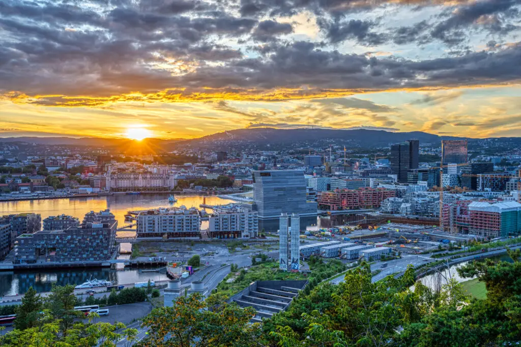 Stunning sunset over Oslo with panoramic cityscape view featuring modern architecture and natural landscapes, ideal for travelers exploring Norway's capital.
