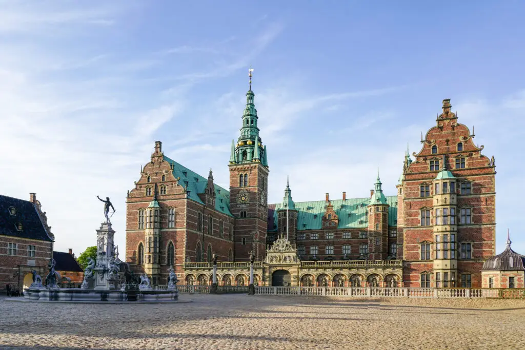 Neptune Fountain in front of the ornate Frederiksborg Castle courtyard facade, Hillerod, Denmark, showcasing Renaissance architecture and historical tourism attraction
