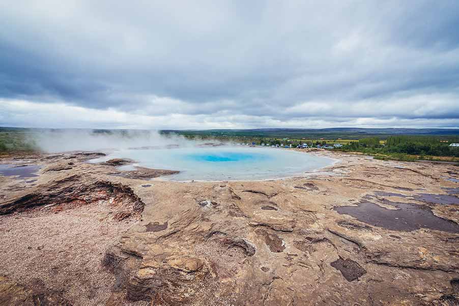 Panoramic view of the Great Geysir in Haukadalur valley, Iceland, showing steaming hot spring and surrounding geothermal landscape.