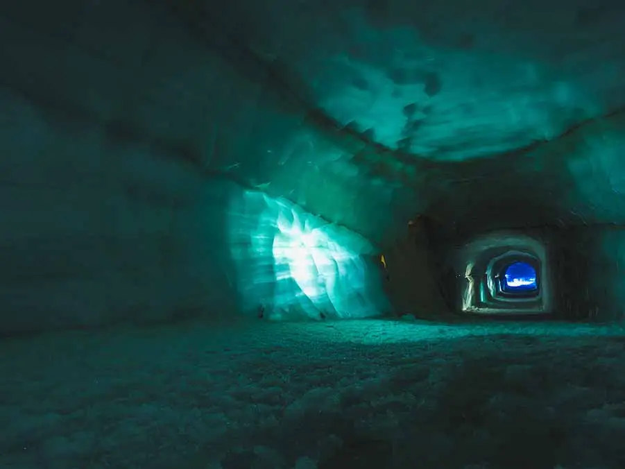 Illuminated ice cave inside Langjokull Glacier in Iceland, showcasing the ethereal blue light and textured ice walls, ideal for a an adventurous tour in Scandinavia.