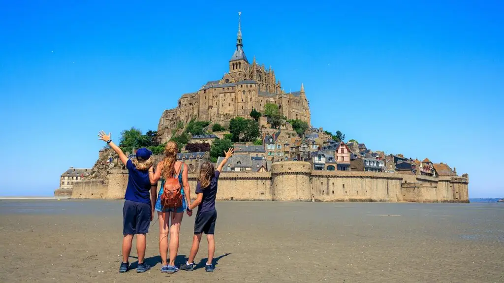 Tourists admiring the majestic Mont Saint Michel in Normandy, a stunning example of medieval architecture and popular travel destination in France.