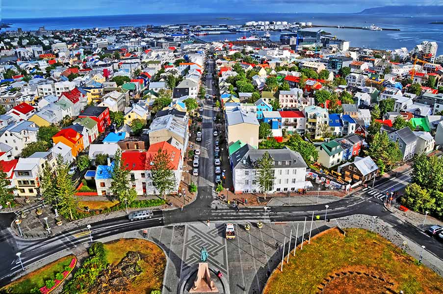 Aerial view of Reykjavík, showcasing the vibrant colorful rooftops and city streets leading to the ocean, highlighting its status as the capital and largest city of Iceland.