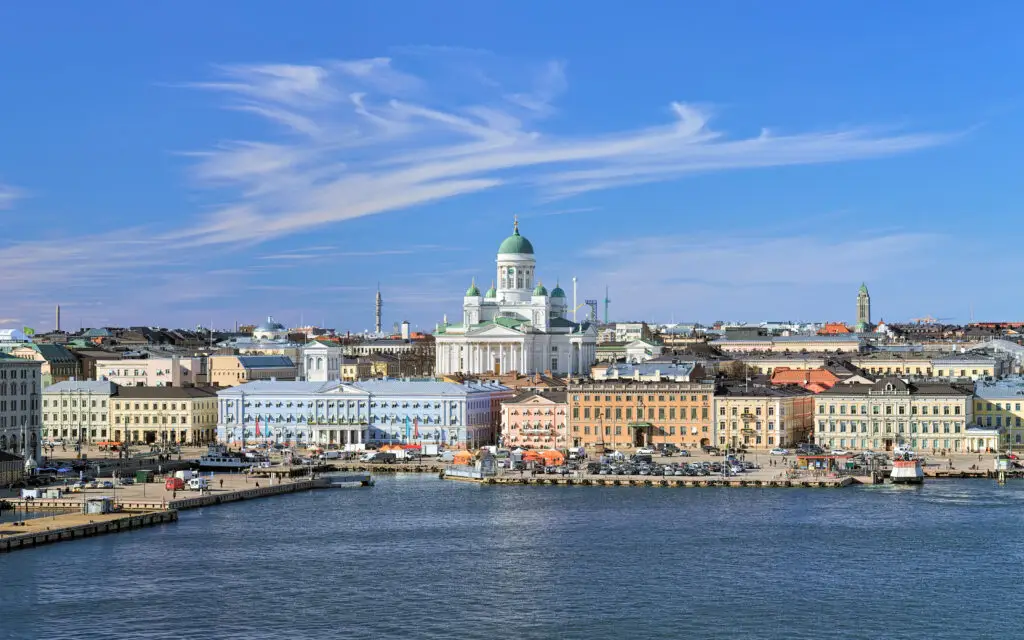 Panoramic view of Helsinki featuring the iconic Helsinki Cathedral, bustling South Harbor, and vibrant Market Square under a blue sky with streaky cirrus clouds, capturing the essence of a sunny spring day in Finland.