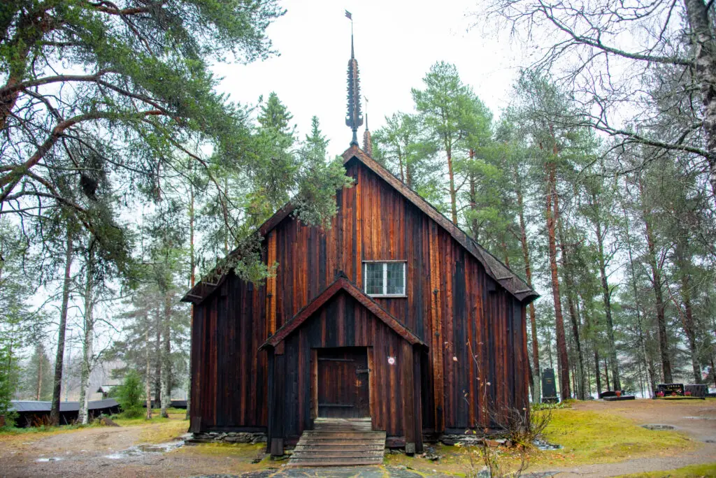 Historic Sodankyla Old Church surrounded by pine trees in Finland, a popular destination for cultural and heritage tourism.