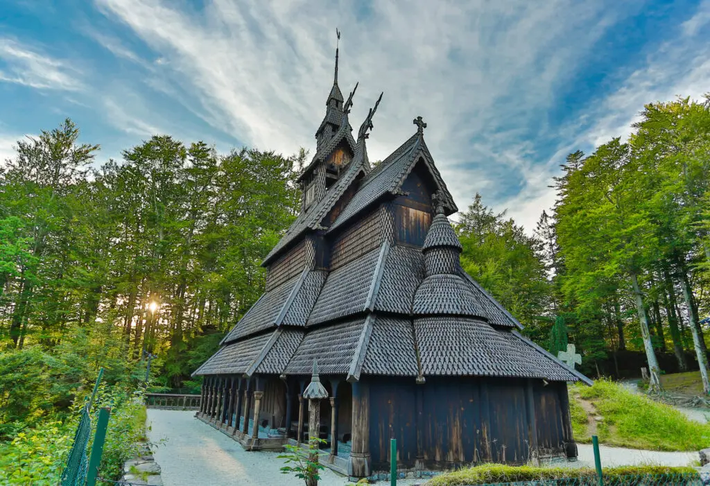 Fantoft Stave Church surrounded by lush greenery under a blue sky in Bergen, Norway, highlighting traditional Norwegian architecture.