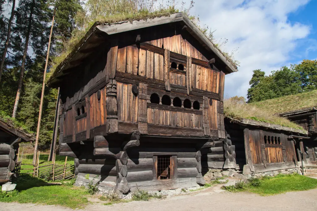 Traditional wooden loft house from Setesdal, Norway, showcasing historical Scandinavian architecture with grass roof, surrounded by forest.