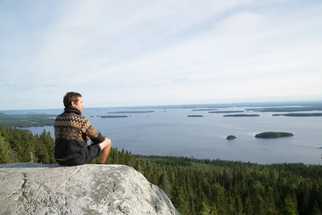 Hiker enjoys the panoramic view of Pielinen Lake from Paha-Koli summit in Finland during summer