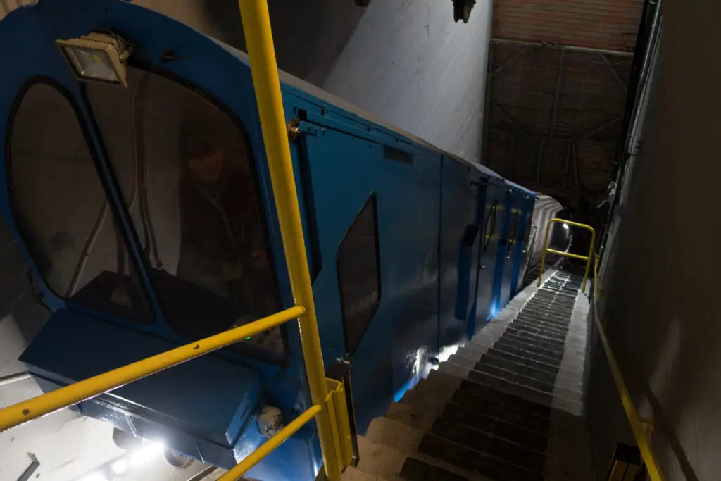 Blue Gaustabanen funicular, accessing Gaustatoppen mountain in Norway, with illuminated entrance and stairs visible, promoting Scandinavian tourism.
