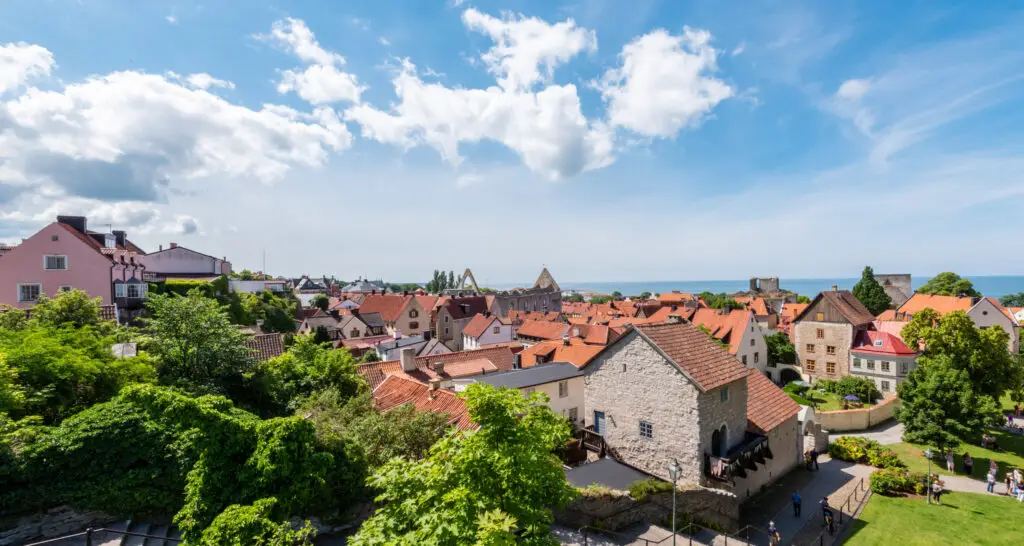 Panoramic view of the Old Town in Gotland, Sweden showcasing historic buildings with red roofs and the Baltic Sea in the background, ideal for tourists exploring Scandinavian heritage.