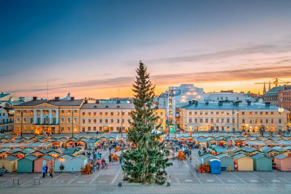 Sunset view of Helsinki Christmas Market with festive lights and a large Christmas tree in Senate Square, Finland