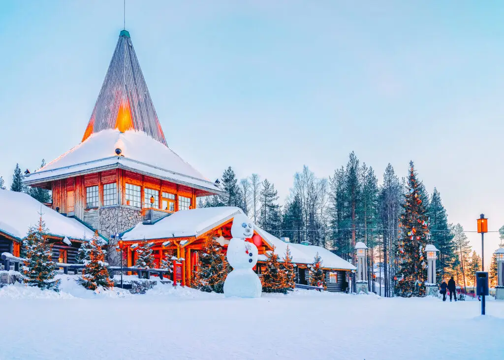 Snowman in front of Santa Office at Santa Claus Village, Rovaniemi Finland, showcasing a scenic snowy landscape with festive decorations and a charming wooden building.