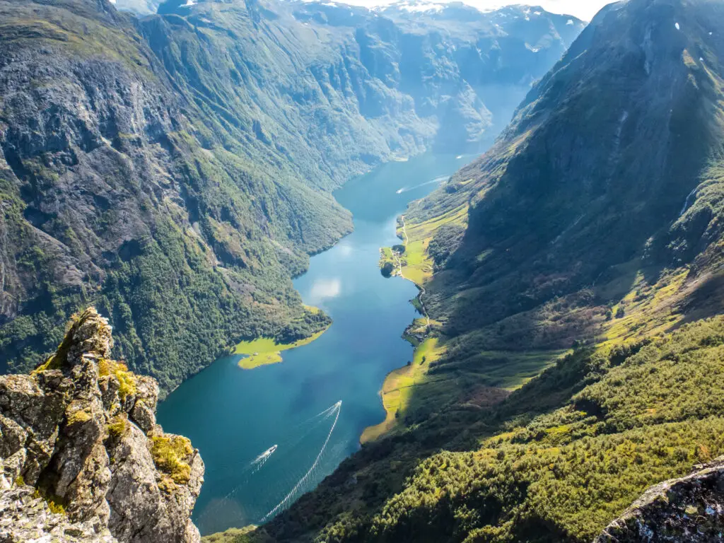 Breathtaking view of Nærøyfjord, a UNESCO World Heritage site in Norway, showcasing steep mountainsides, lush greenery, and serene waters with boats sailing.
