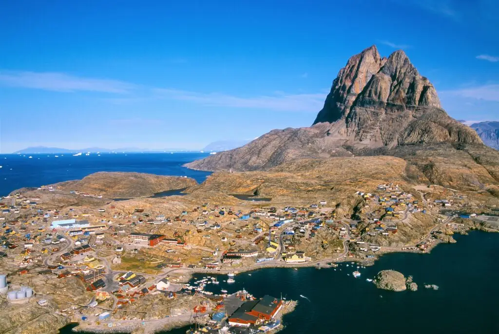 Aerial view of Uummannaq town and dramatic mountain landscape in West Greenland, highlighting the unique Arctic tourism destination.