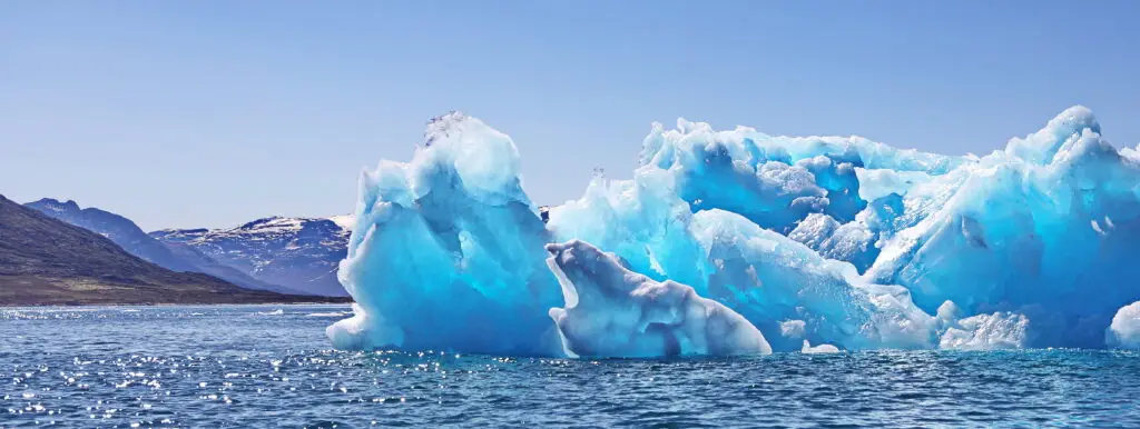 Stunning view of icebergs and clear blue waters in Nuuk Fjord, Greenland, highlighting the serene yet dynamic Arctic landscape.