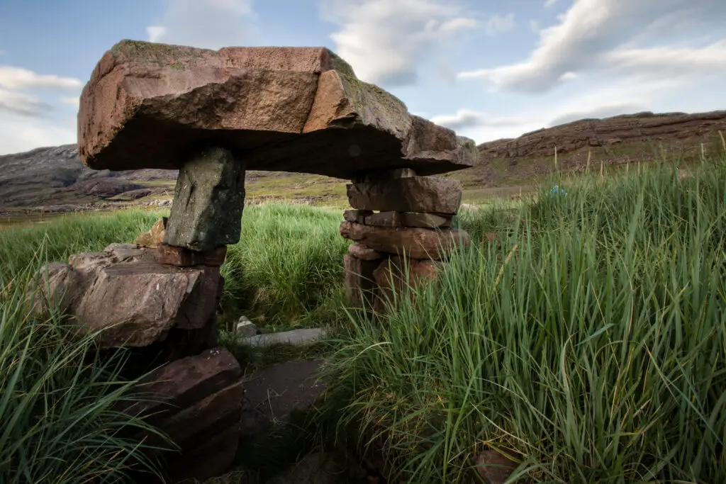 Ancient Norse ruin in Igaliku, Gardar, Greenland showcasing a stone structure amidst lush green grass with mountains in the background.