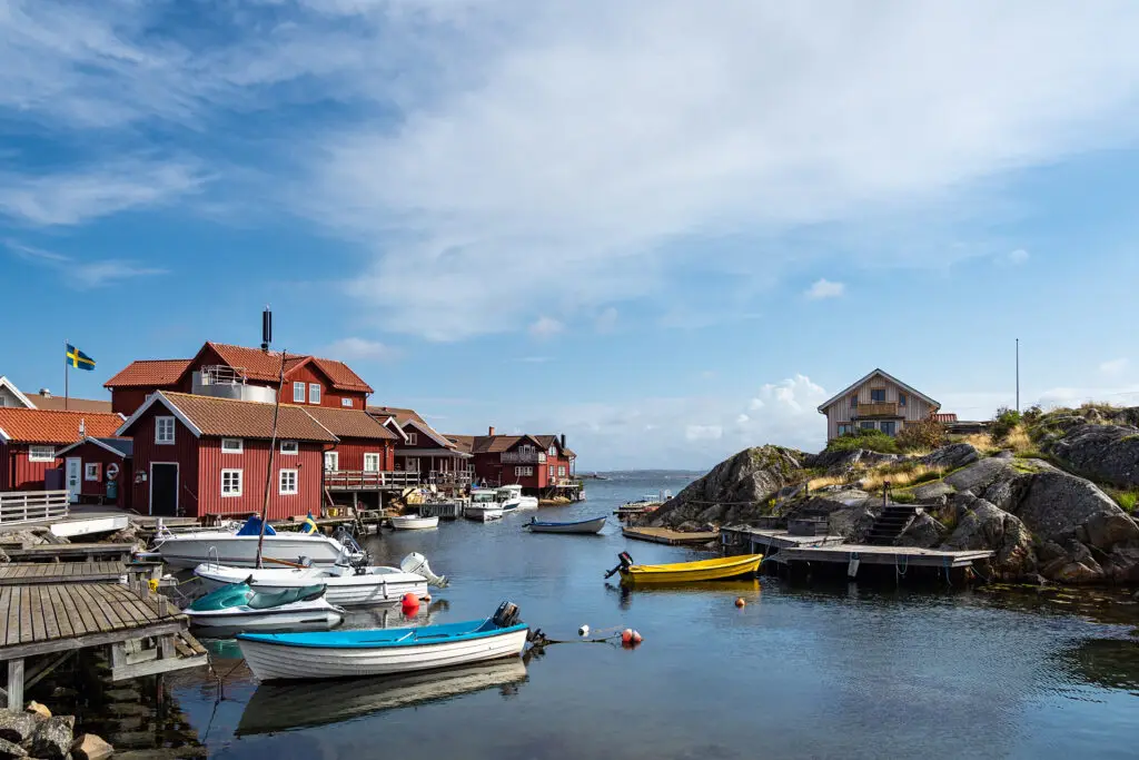Scenic view of Käringön Island in Sweden showcasing traditional red wooden houses and docked boats under a clear blue sky.
