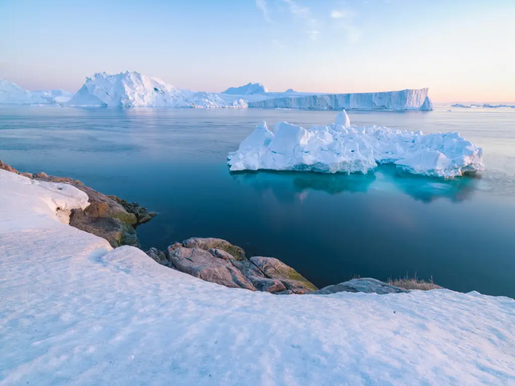 Breathtaking view of icebergs and glaciers at sunset in Greenland, showcasing the serene beauty of Arctic landscapes perfect for nature tours.