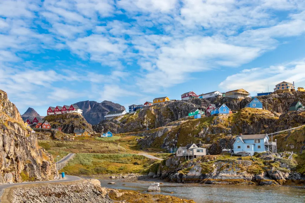 Colorful houses and diverse architecture on rocky terrain in Sisimiut, Greenland, showcasing a scenic view of a popular tourist destination in Scandinavia.
