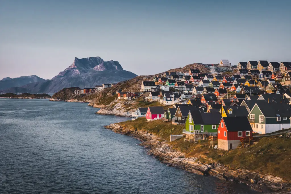 View of colorful houses in Myggedalen, Nuuk, during a vibrant sunset with Sermitsiaq Mountain in the background, illustrating a classic Greenlandic landscape.