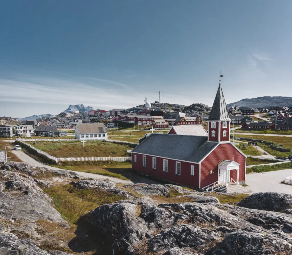 Nuuk Church Cathedral Annaassisitta Oqaluffia, Church of Our Saviour, in the historic center of Nuuk, Greenland, on a sunny day with blue skies and rocky mountainous backdrop.
