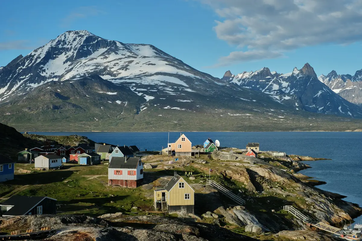 Colorful houses in Tasiusaq, Greenland overlooking a fjord with snowy mountains in the background