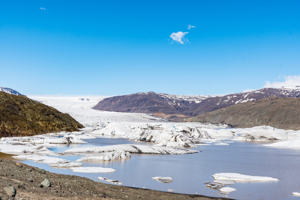Panoramic view of Hoffellsjokull Glacier and Lagoon with floating icebergs in South Iceland, depicting the stunning icy landscape and clear blue skies, ideal for educational and sightseeing tours in Scandinavia.