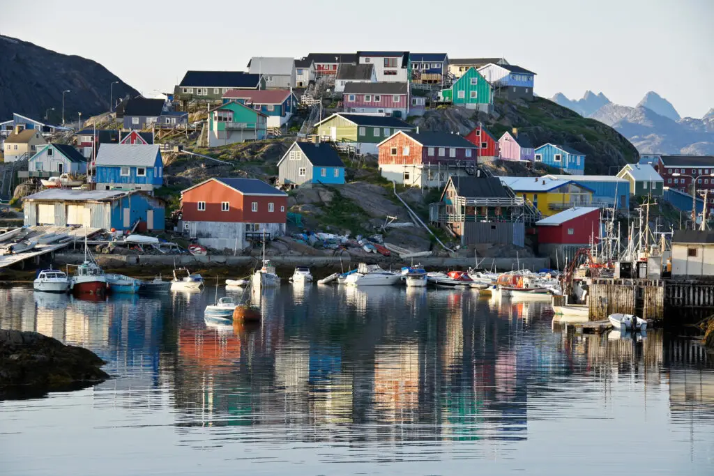 Colorful houses and boats in the harbor of Maniitsoq, Greenland, showcasing the town's unique terrain and architecture.