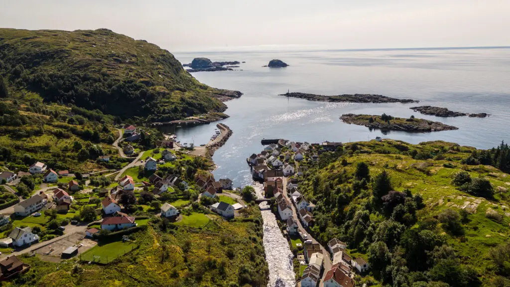 Aerial view of Sogndalsstrand village in Norway showcasing quaint houses, winding roads, and a serene coastline, perfect for a picturesque Scandinavian tour.