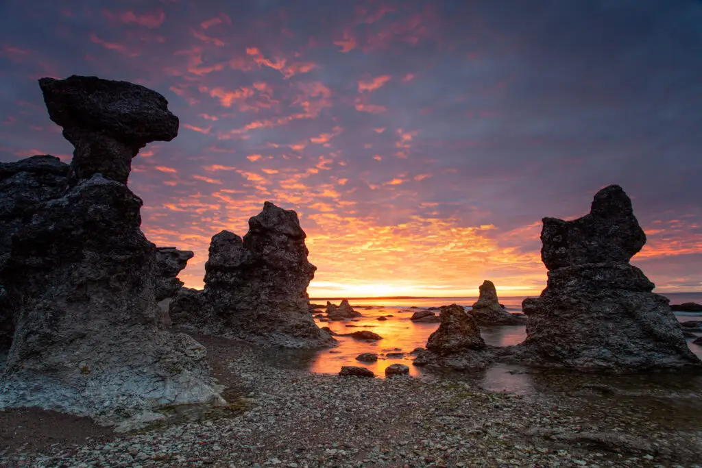 Sunrise over the Baltic Sea illuminating the distinctive rauk-fields of Gotland, showcasing ancient limestone formations on a rocky beach.