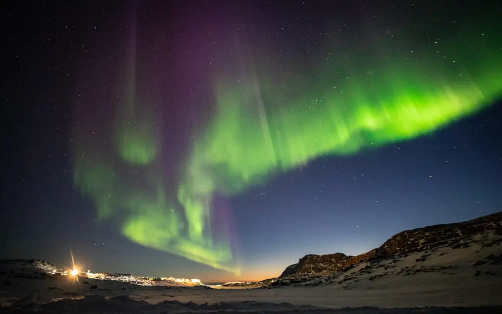 Northern lights illuminating the night sky over Sisimiut town, Greenland during winter, a prime Scandinavian tourism destination