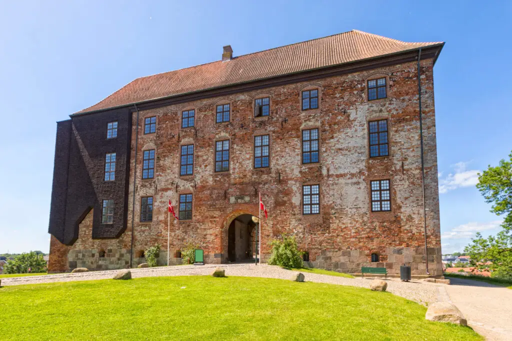 Exterior view of Koldinghus Castle in Kolding, Denmark showcasing the historical architecture and lush green surroundings, a prominent tourist destination and museum.
