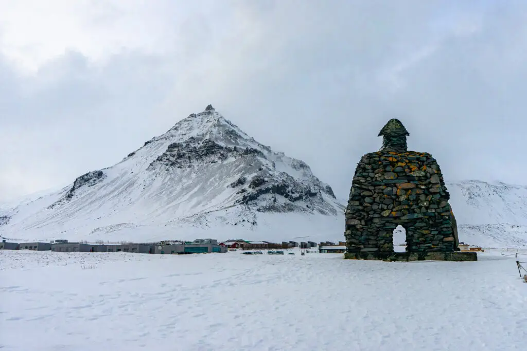 Saga of Barour Snaefellsas statue covered in snow at Arnarstapi, Snæfellsnes Peninsula, Iceland, highlighting the dramatic winter landscape and cultural heritage.