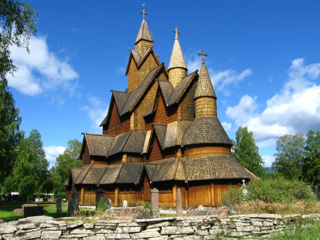Heddal Stave Church in Norway, an iconic wooden church dating back to the 13th century, surrounded by green landscape under blue skies.