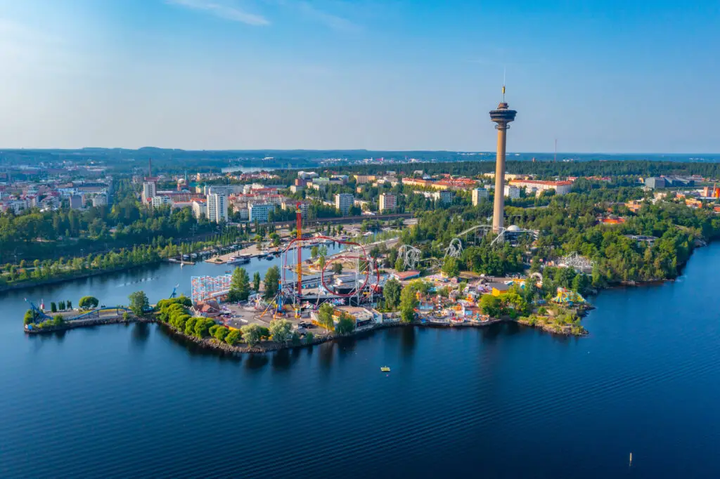 Aerial view of Särkänniemi Amusement Park in Tampere, Finland showcasing roller coasters, outdoor attractions, and Näsinneula Tower by the lake.