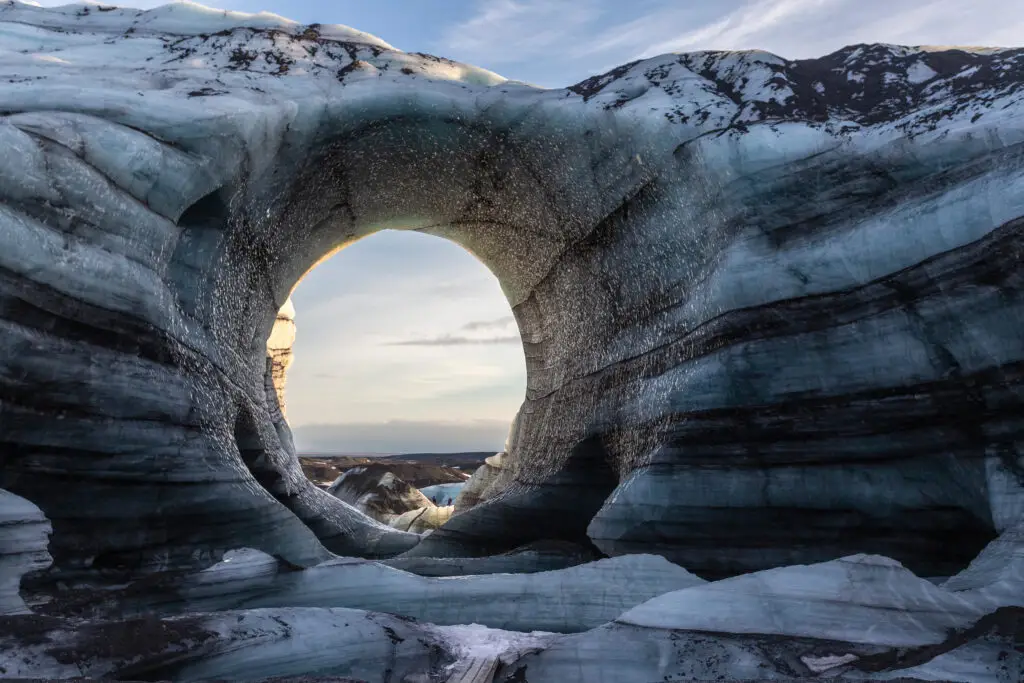 Winter tour of the majestic Katla Glacier ice cave in Iceland, showcasing the stunning arch and layered ice formations.