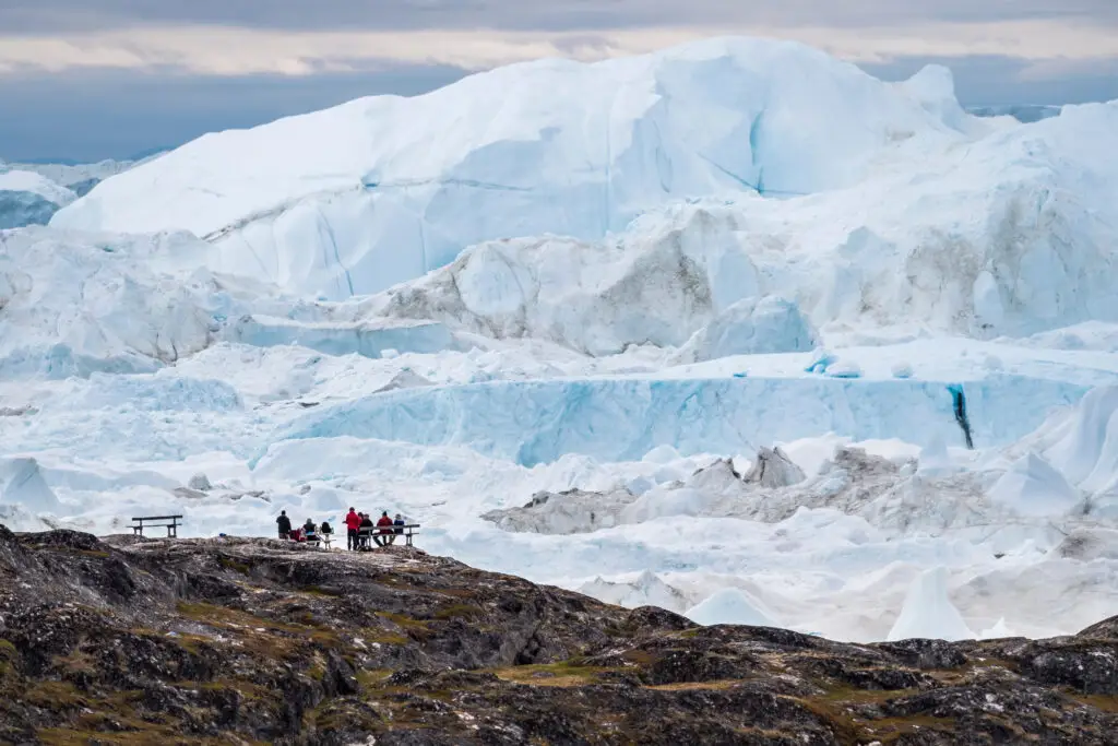 Tourists enjoying the vast icebergs of Disko Bay, Greenland, showcasing the unique icy landscape and extreme tourism.